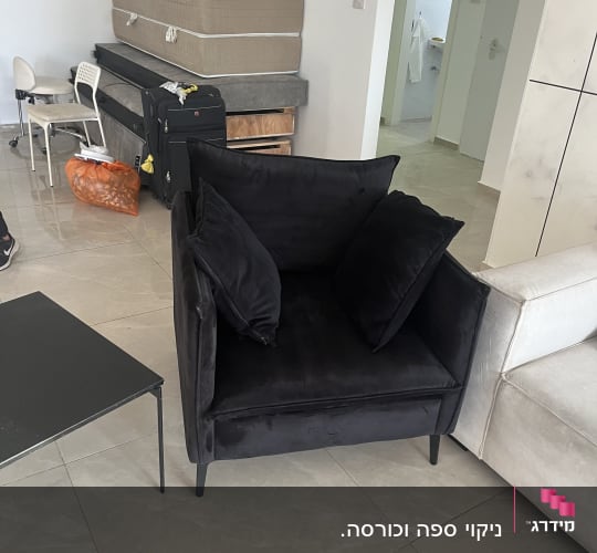 ספה שחורה בחדר עם מזרנים וכיסאות